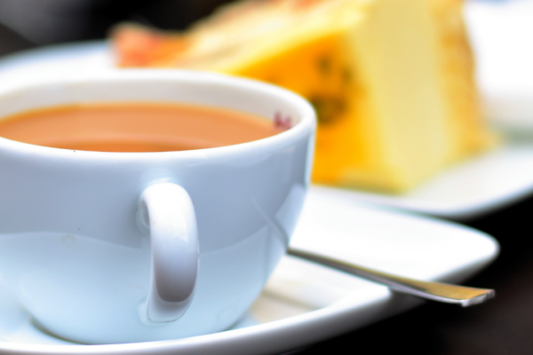 An image of a cup of tea and a piece of yellow cake