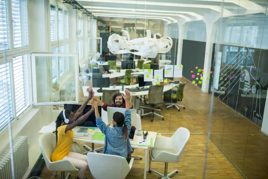 A group graphic designers giving high five to each other in the office.