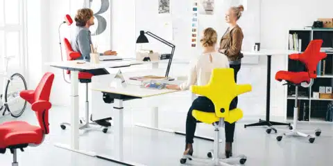 A number of people sitting on bright ergonomic chairs,