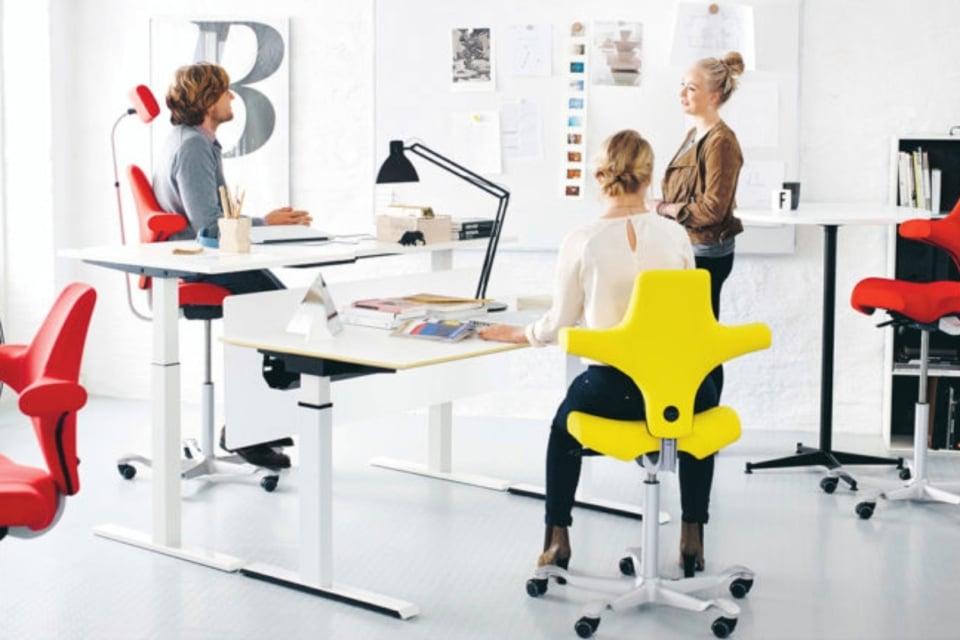 A number of people sitting on bright ergonomic chairs,