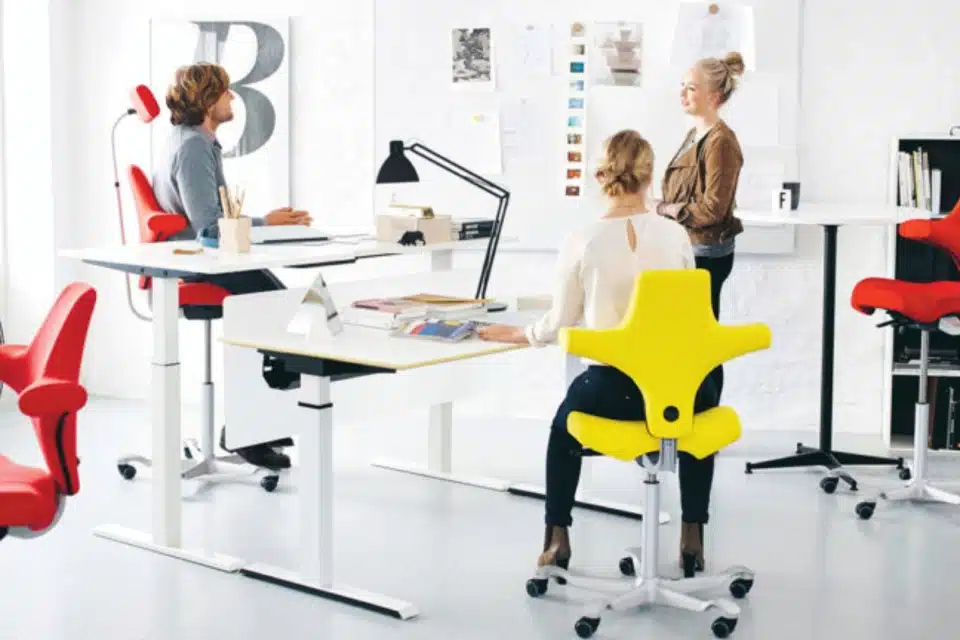 A number of people sitting on bright ergonomic chairs,