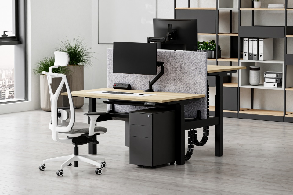 A single standing bench desk in a room with shelves in the background.