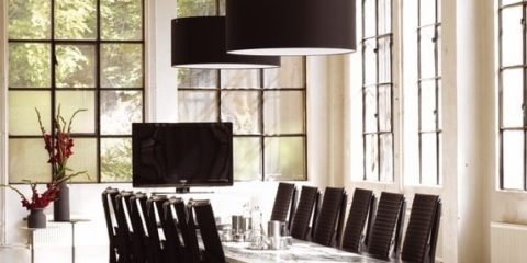 A row of black leather HÅG Excellence ergonomic boardroom chairs arranged around a large table in a spacious modern office.