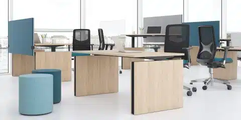 A standing wooden desk in empty office with blue acoustic panels.