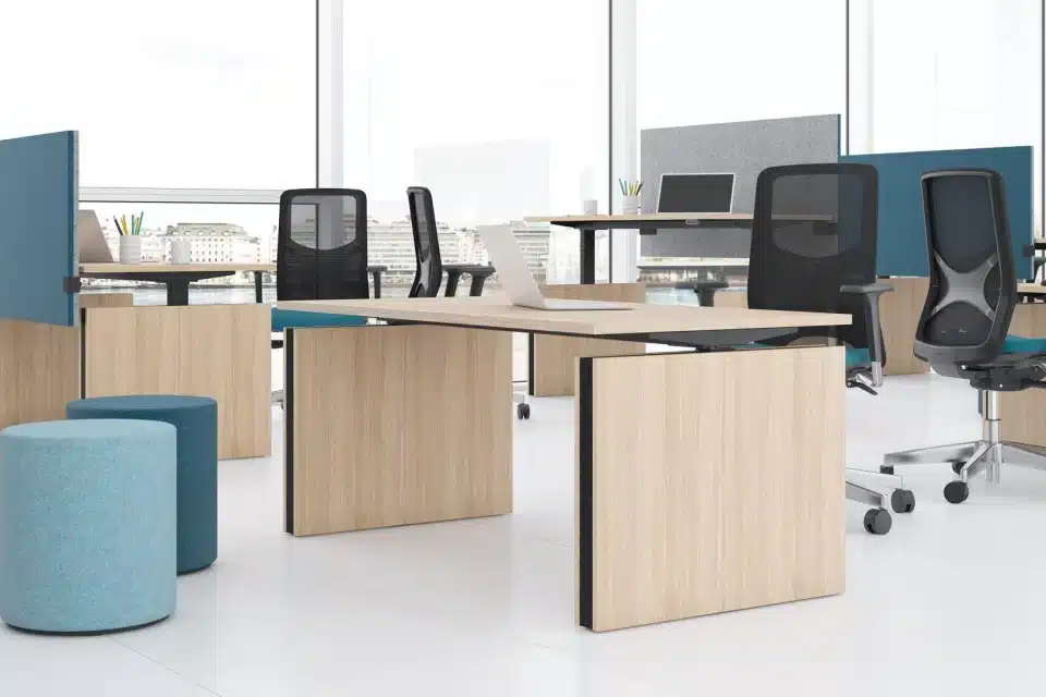A standing wooden desk in empty office with blue acoustic panels.