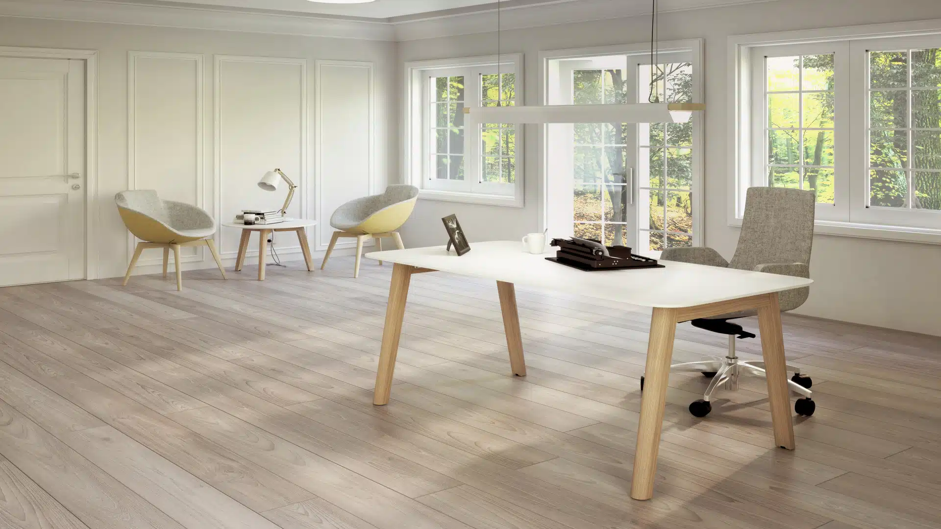A bright, modern office room with two natural wood desks, white tabletops, and two computer monitors positioned for work.