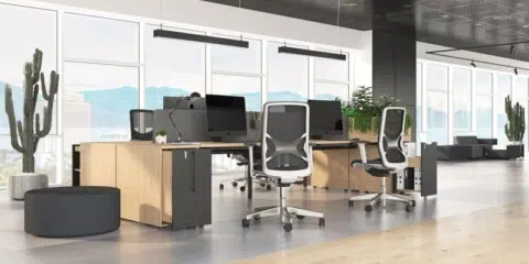 A large office room filled with bench desks, task chairs and green planters.