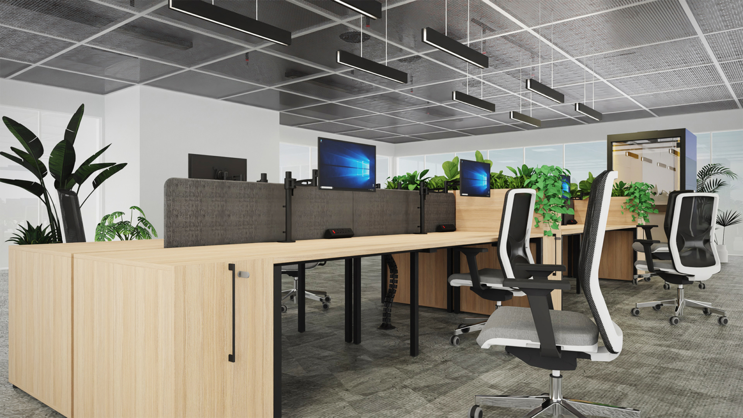 A room with large row of bench desks with acoustic dividers and desktops in an industrial style room.