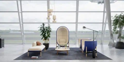 Cream and dark blue, egg shaped pod placed in a large waiting room with a huge window behind.