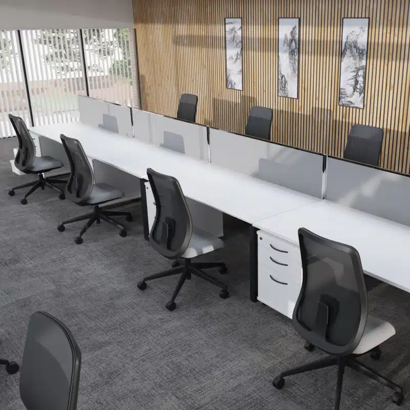 A row of white desks with ergonomic black chairs in a modern office featuring gray carpeting.