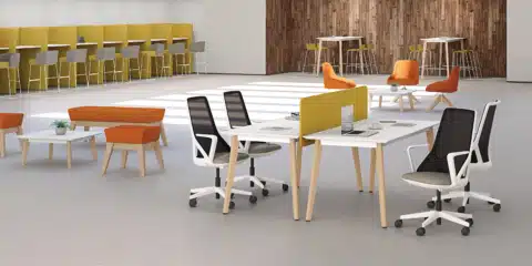 Bench desk wooden style tables in a large room with white office chairs.