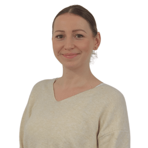 A female colleague smiling in front of a white wall.