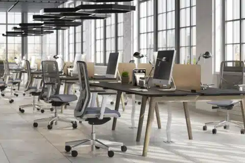 An open plan room with a row of bench desks and ergonomic task mech chairs.