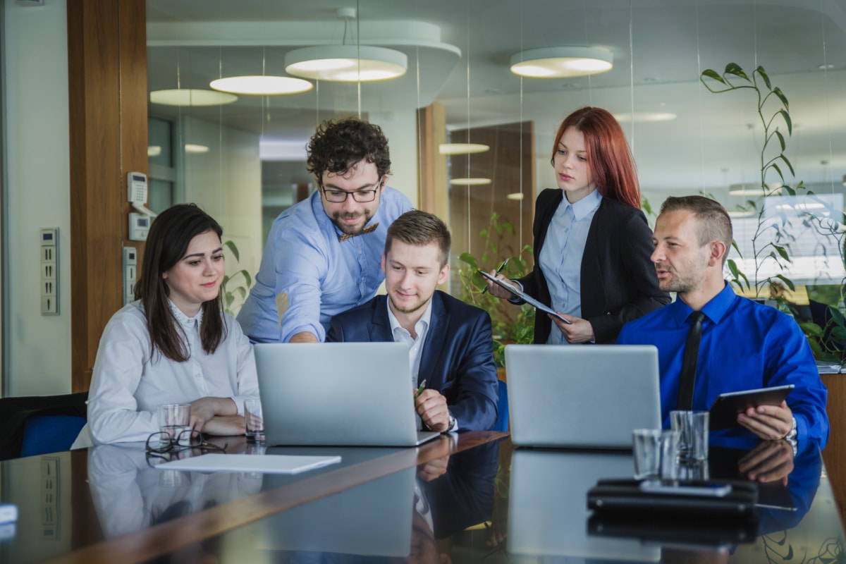 A group of creative people viewing a presentation on their colleagues laptop.