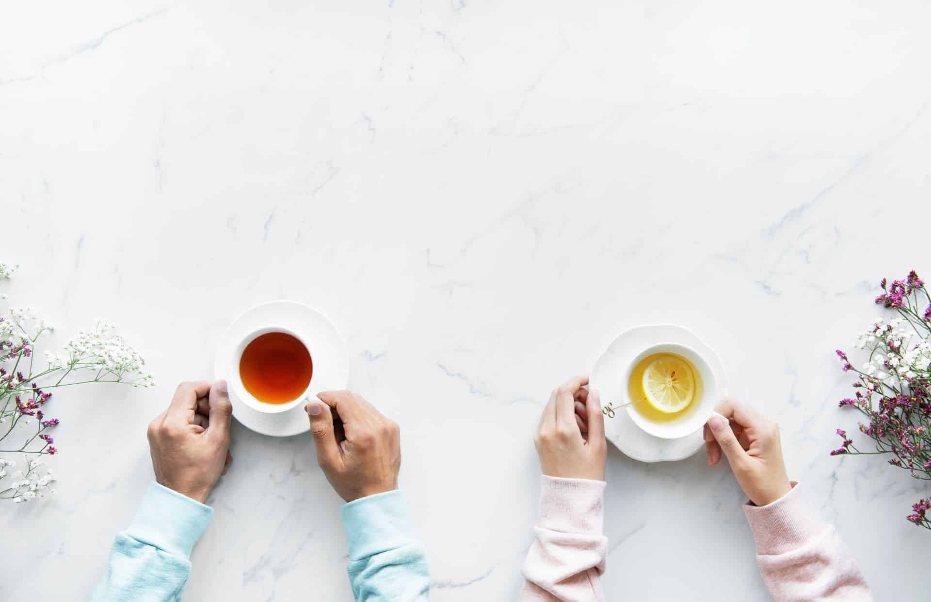 A group of people is enjoying a cup of tea together in a white room.