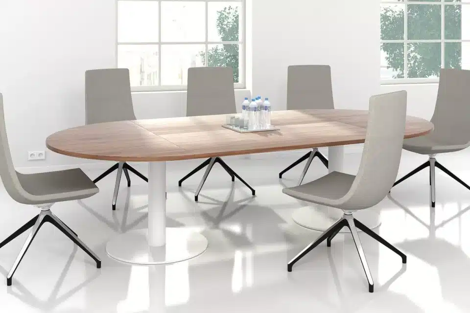 A wide meeting table with grey chairs.