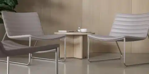A coffee table next to two high lounge chairs.