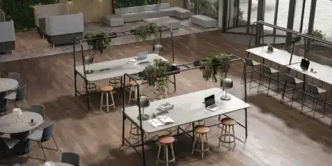 A large room with high tables with green planters on top.
