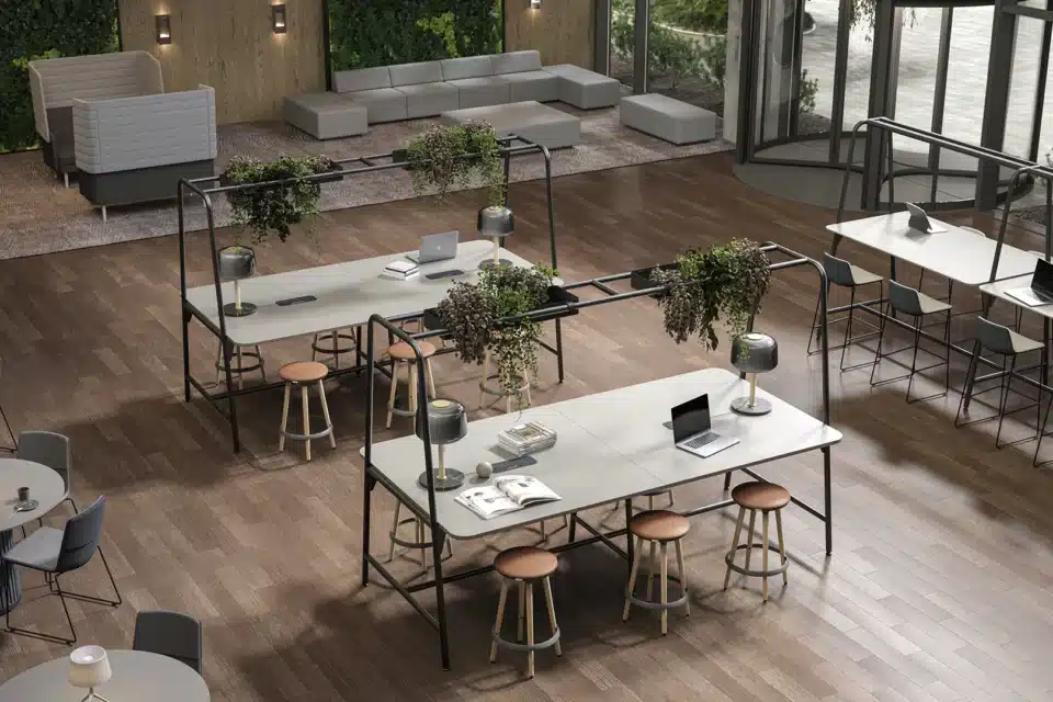 A large room with high tables with green planters on top.