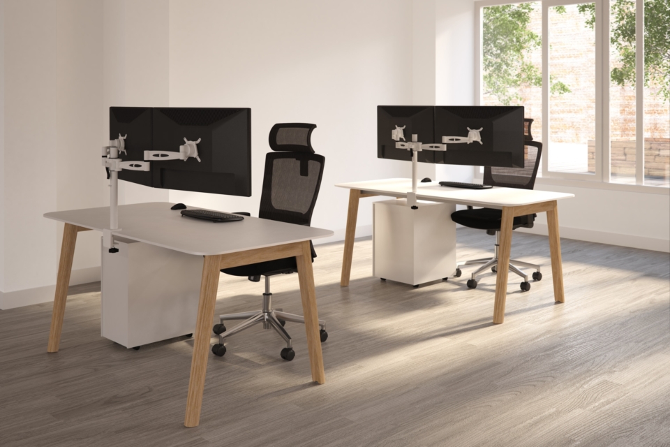 A wooden bench desk with black mesh office chairs.