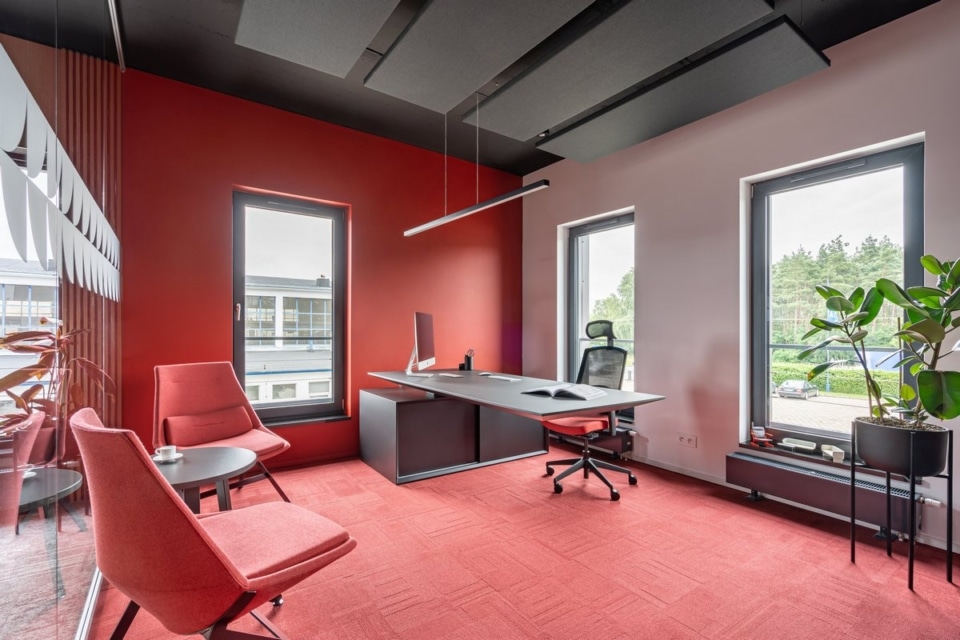 A sleek MDD Gravity executive desk and ergonomic chair inside a spacious, modern red executive office.