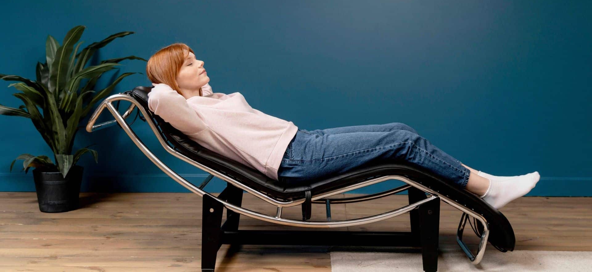 A woman resting on a sofa chair in an office.