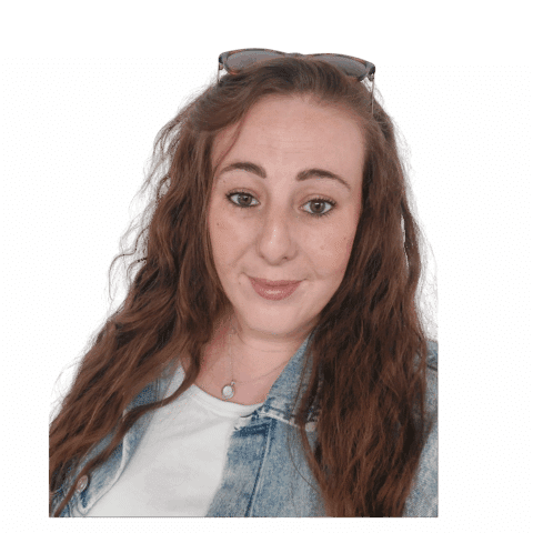 A lady with long curly hair standing in front of a white wall.