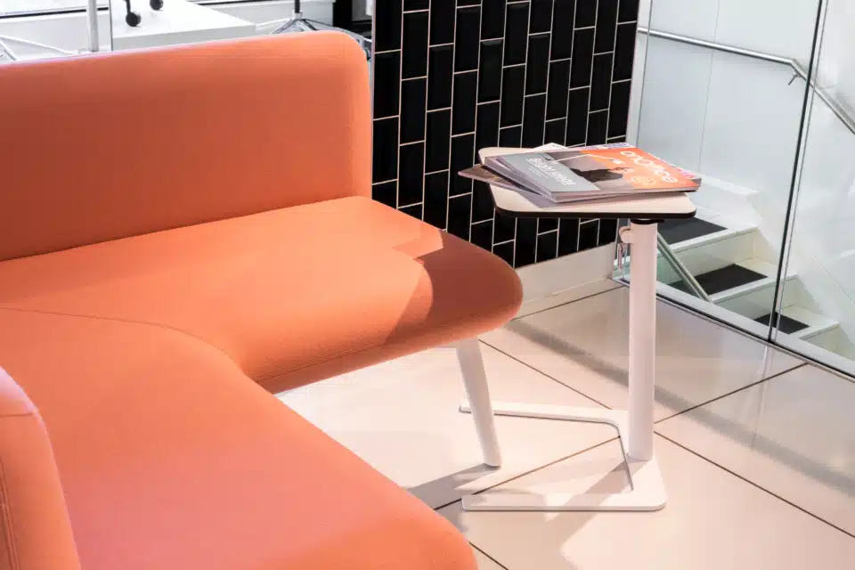 An coral modular sofa that is in a room with a side table.