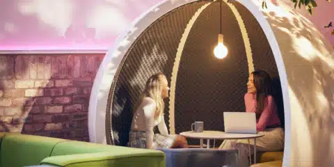 A white escape pod in a pink and green room.