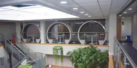 A room with stairs and three white open acoustic pods.