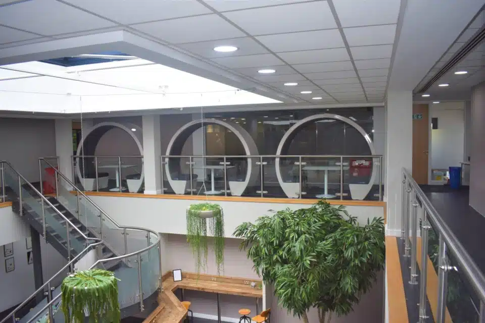 A room with stairs and three white open acoustic pods.