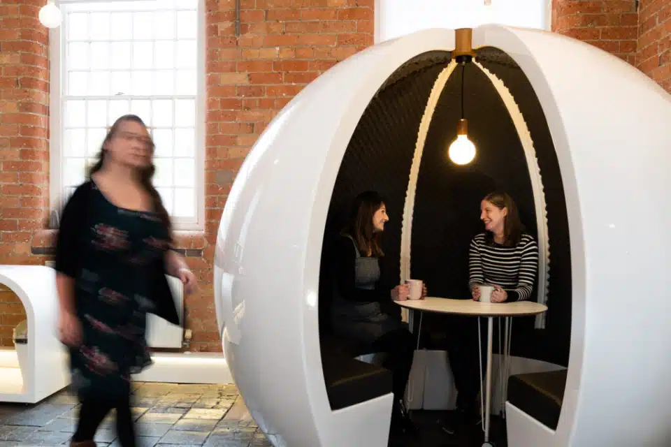 A white round pod with two people sitting indise.