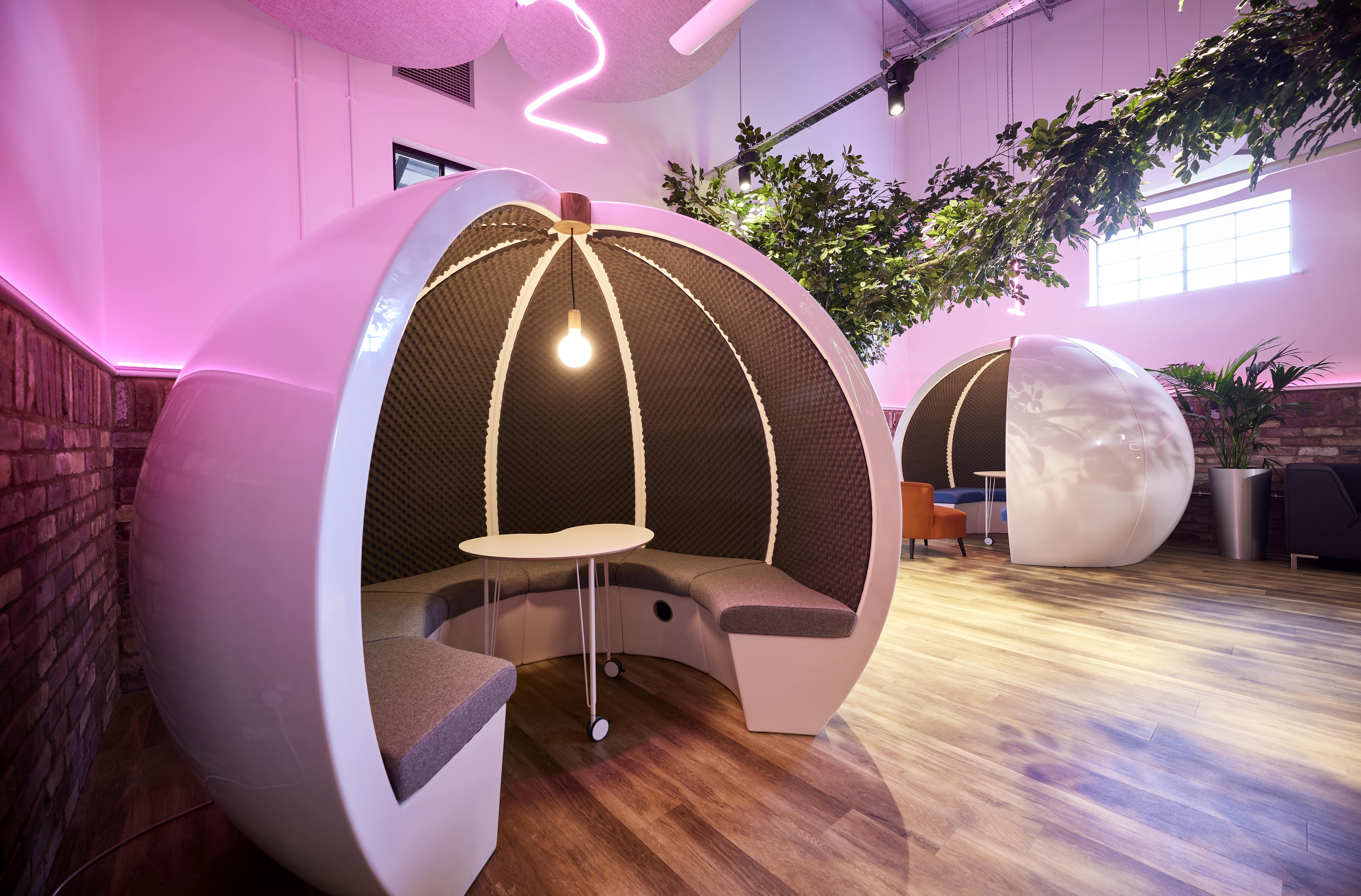 A room with a white open acoustic pod.