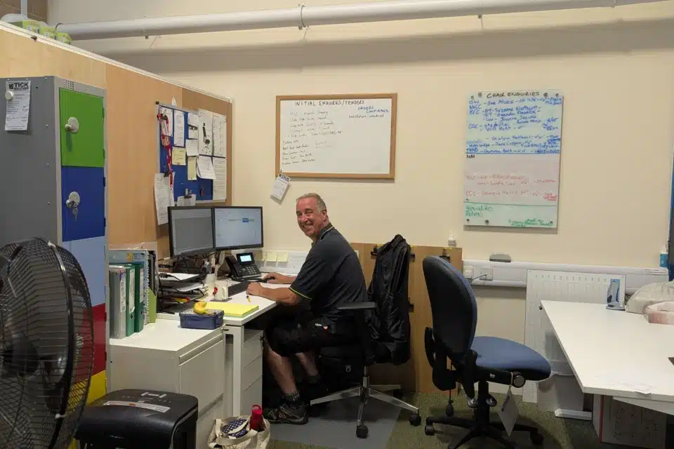 A happy male warehouse expert smiling at his desk at the end of a successful day.