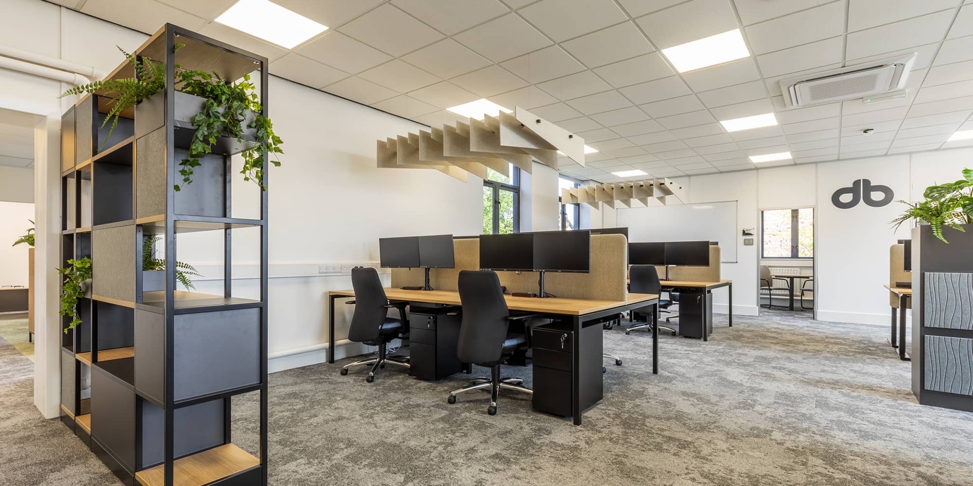 Modern open plan office featuring integrated desks, acoustic sound baffles, and a functional storage wall barrier.