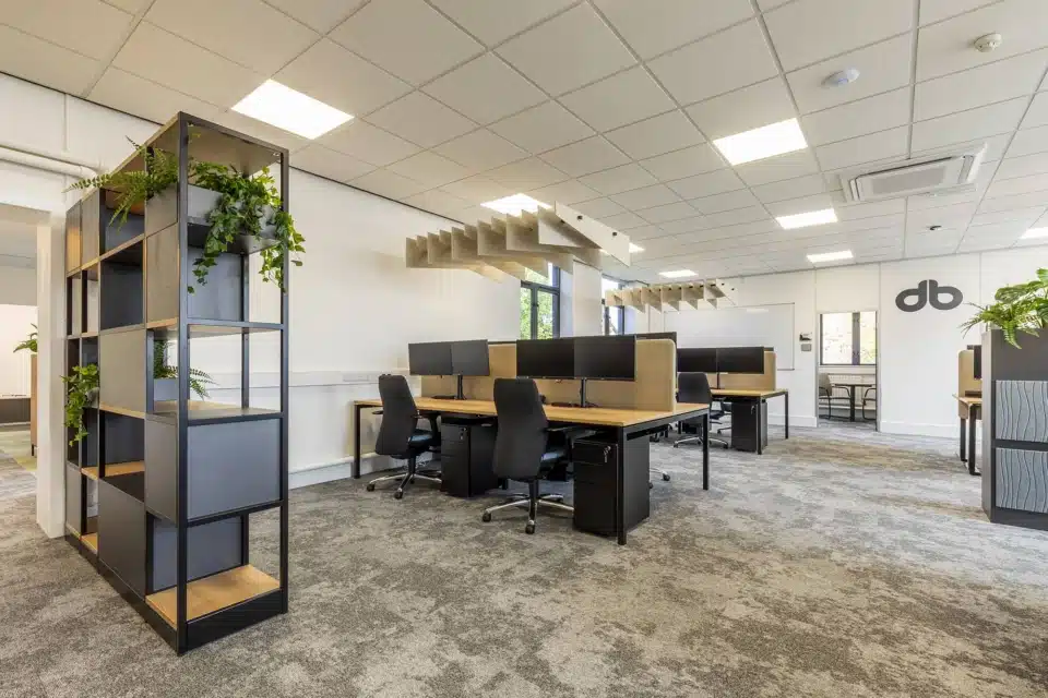 Modern open plan office featuring integrated desks, acoustic sound baffles, and a functional storage wall barrier.