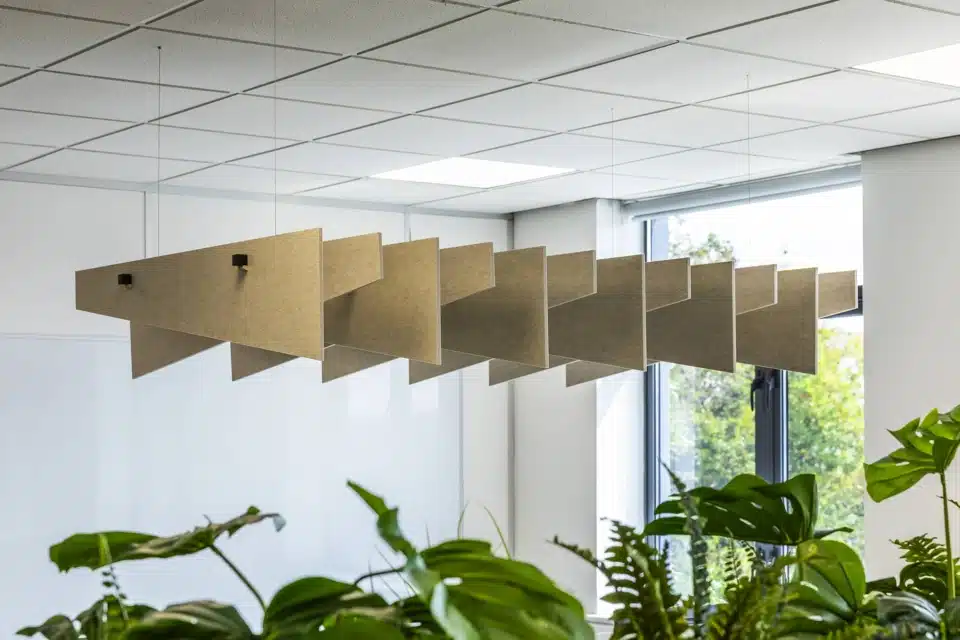 A close-up view of ceiling baffles and storage lockers with plants.