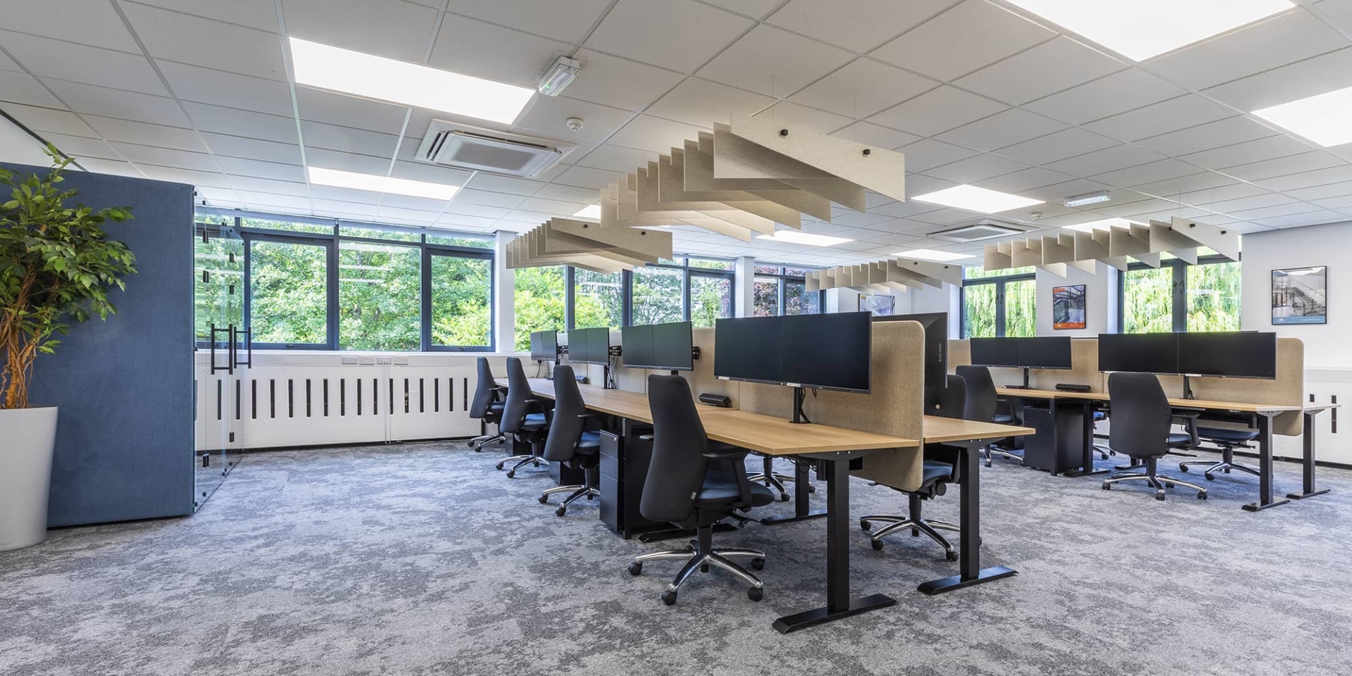 A large office room with several desks and ergonomic chairs.