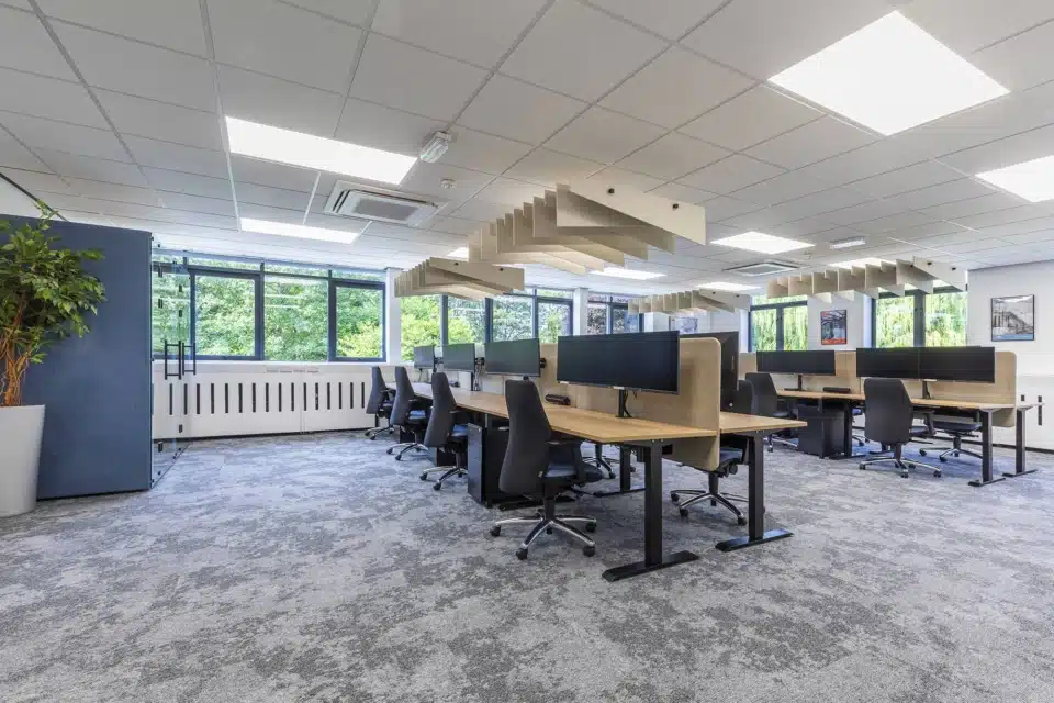 A large office room with several desks and ergonomic chairs.