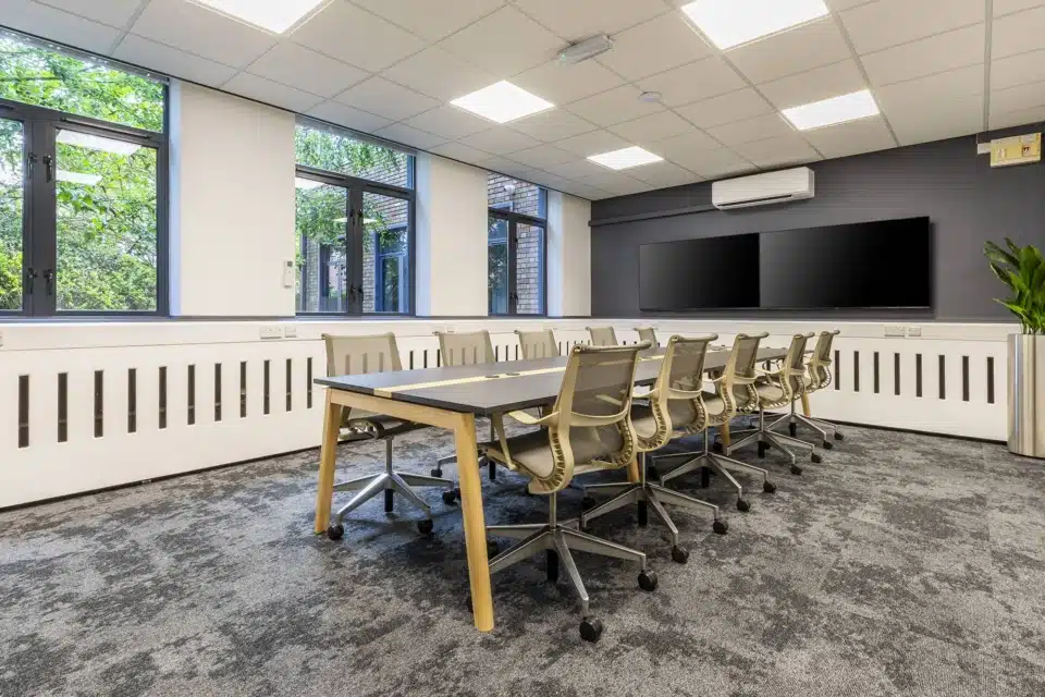 A large room with boardroom table and ergonomic chairs.