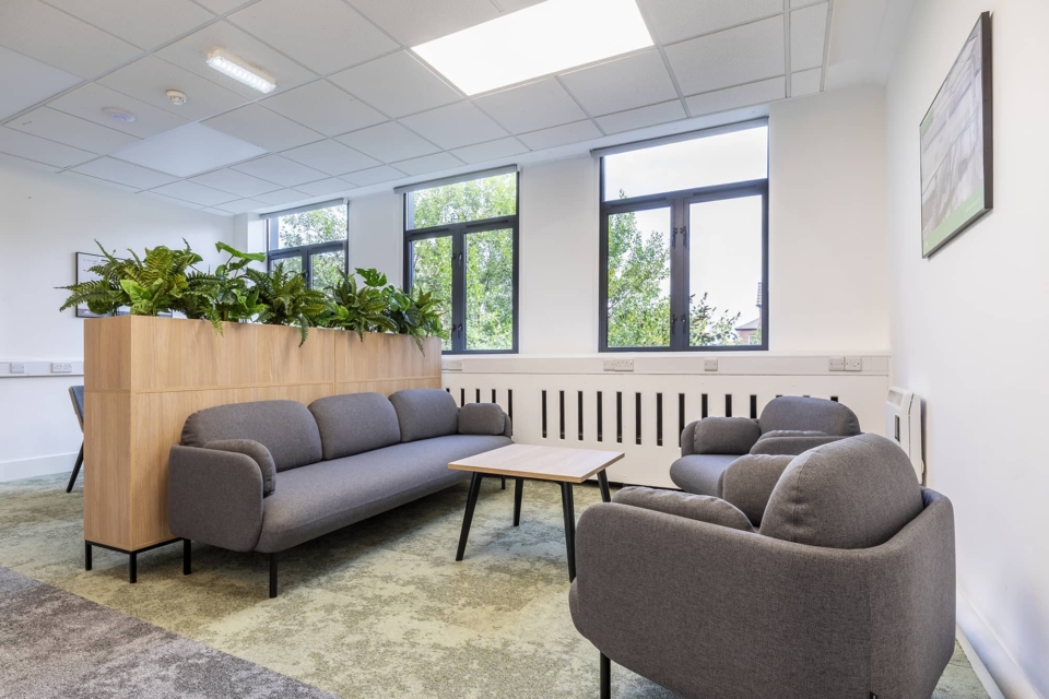 A living room with blue sofas and planters.