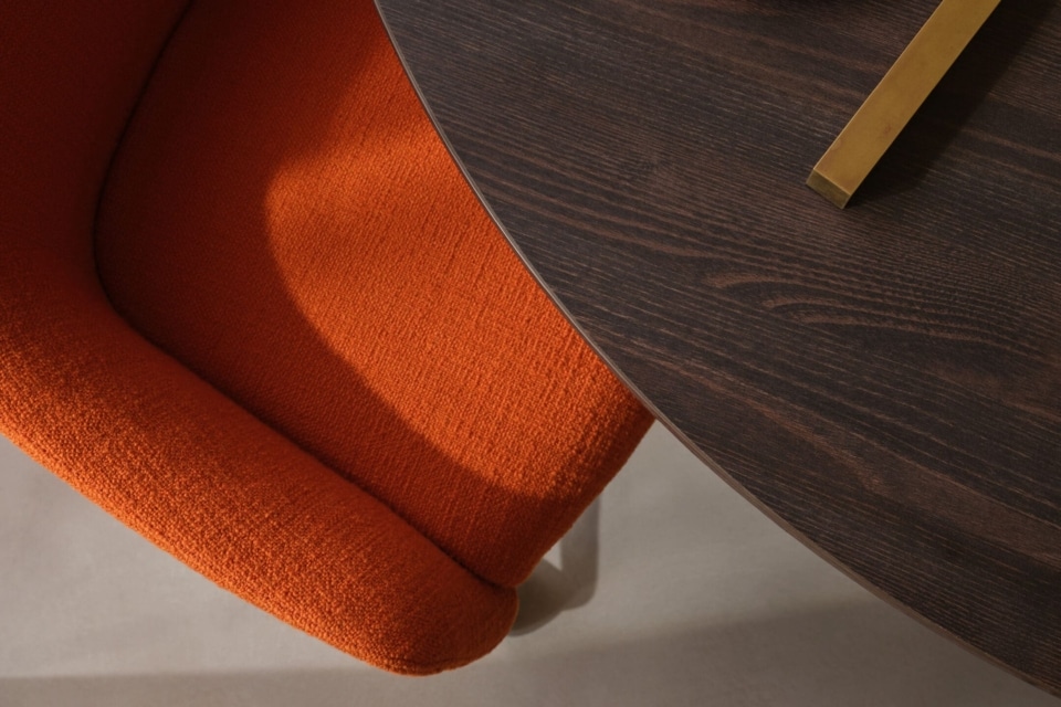 Close-up of a bright orange boucle upholstered chair.
