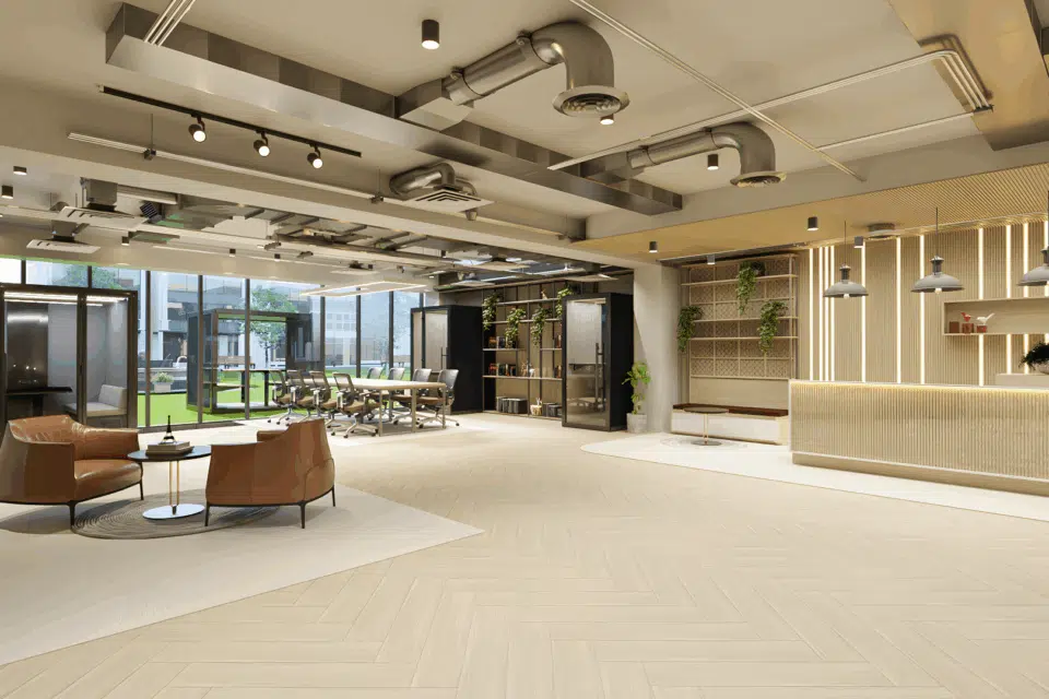 A modern open-plan office featuring a long light-wood communal table with ergonomic chairs and several sleek acoustic indoor work pods in the background.