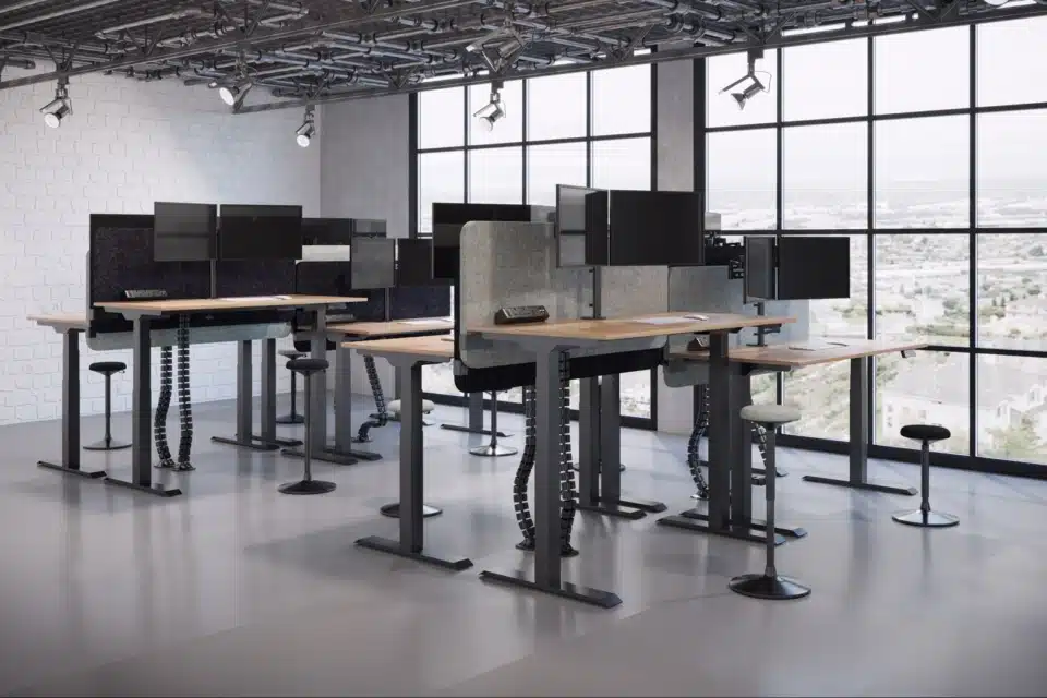 Industrial office with adjustable desks, monitors, and screens.