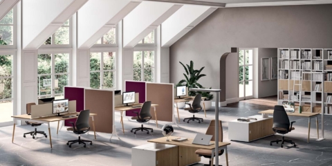 Collaborative X3 desks in a bright room with screens and divider panels.