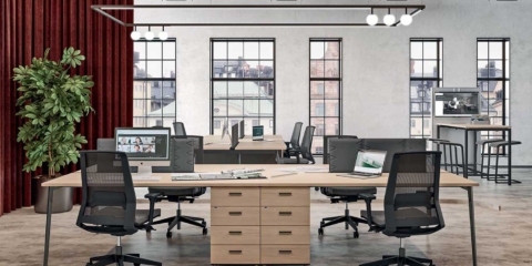 Collaborative X3 desks in a bright room with screens and divider panels.
