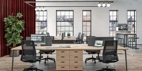 Collaborative X3 desks in a bright room with screens and divider panels.