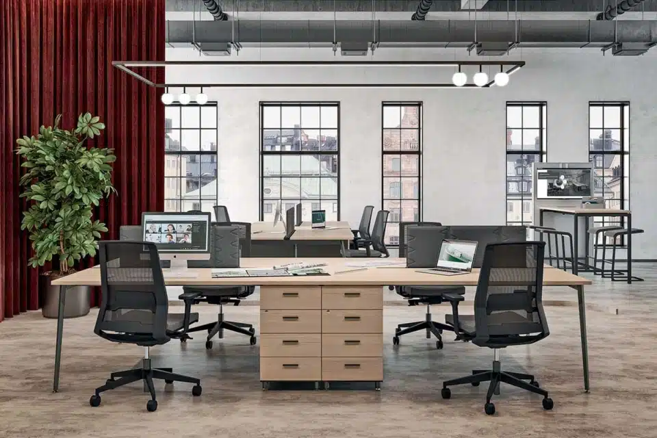 Collaborative X3 desks in a bright room with screens and divider panels.