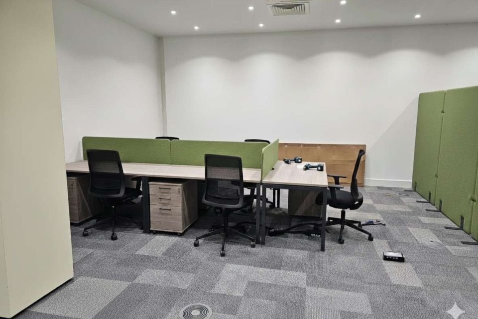 Contemporary back-to-back office workstations featuring light oak desks, lime green privacy screens, and black mesh ergonomic chairs arranged on grey carpet.