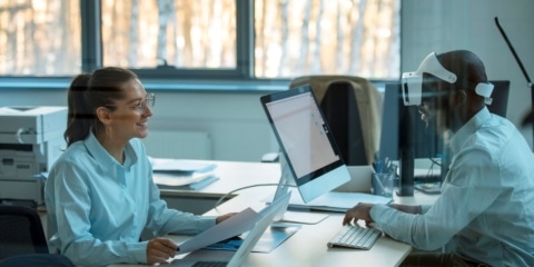 Two colleagues in a modern, bright office working together at a long desk.